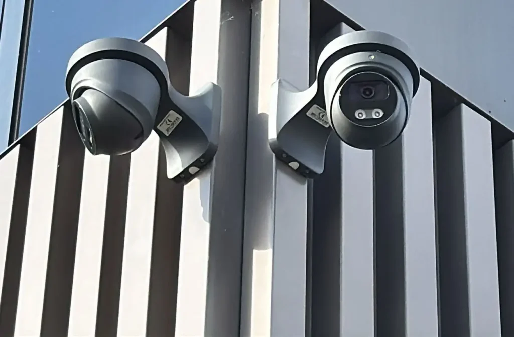 Zwei schwarze Dome Überwachungskameras an einer modernen Gebäudefassade installiert, zeigen professionelle Sicherheitslösung für Unternehmen und Gewerbe